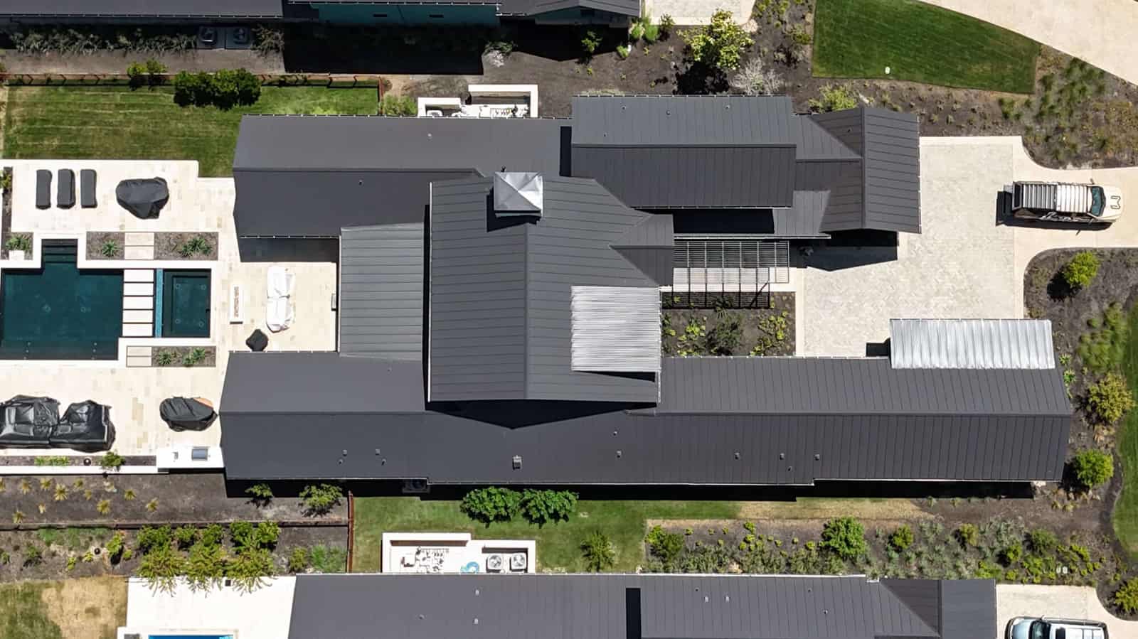 Overhead drone view of a large Hill Country home with a dark standing-seam metal roof