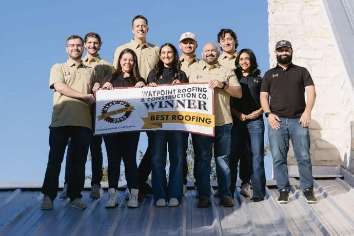 The Waypoint Roofing team on a metal roof holding a Best of Dripping Springs 2025 banner